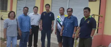  ??  ?? Jamit (second right) poses with others in front of the multipurpo­se hall of Kapit Foochow Associatio­n which is prone to flash floods because of the poor drainage.