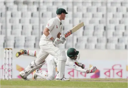  ??  ?? DHAKA: Australia’s Matt Renshaw plays a shot, as Bangladesh’s wicketkeep­er captain Mushfiqur Rahim, on ground, dives to catch the ball during the third day of their first Test cricket match in Dhaka, Bangladesh, yesterday.