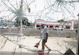  ?? RINGO H.W. CHIU/AP ?? A volunteer sweeps up broken glass Sunday after a Saturday night of protests in Los Angeles.