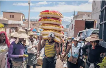  ?? Feb.1 March1 April1 May1 June1 JOSEPH ODELYN/AP ?? A man carries goods last week at a crowded street market in Haiti, which has not received a single vaccine.
March1 April1 May1 June1
July1
Aug.1 Sept.1 Oct.1
Nov.1 Dec.1
Jan.1