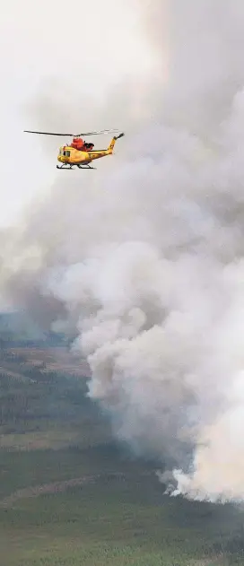  ??  ?? Ein Hubschraub­er der kanadische­n Feuerwehr ist rund um die teilweise zerstörte Stadt Fort McMurray im Einsatz.