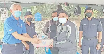  ??  ?? Hazani (right) receiving a contributi­on on behalf of the security personnel manning the roadblock at Mile 2, Apas Road yesterday. Hazani is on a statewide tour to inspect all 57 roadblocks in Sabah.