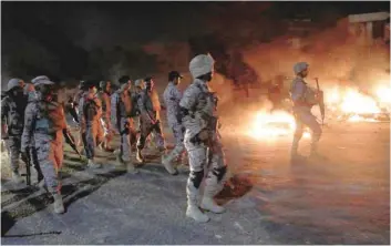  ?? — Reuters ?? Paramilita­ry soldiers walk past burning bikes, during a protest after dispersing the supporters of the Tehreek-labaik Pakistan, in Karachi on Saturday.