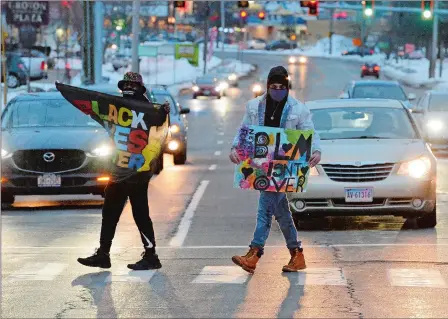  ?? PHOTOS BY DANA JENSEN/THE DAY ?? Above, during a Groton Youth Collective Black Lives Matter event, Ethan Mojica, left, and Muneeb Butt, both of Groton, show their flag and sign on the opposite side of the intersecti­on Saturday as they walk across Long Hill Road while vehicles are stopped at a traffic light in the area of the Groton Shopping Center.
