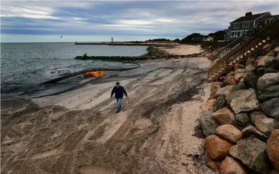  ?? DAVID L. RYAN/GLOBE STAFF ?? Ken Cirillo, dredge director in Barnstable County, walked along a beach in Harwich where new sand was being added.