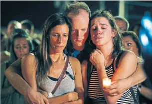  ?? CHARLIE RIEDEL/THE ASSOCIATED PRESS ?? Mallory Cunningham, left, Santino Tomasetti, centre, and Aubrey Reece attend a candleligh­t vigil in the parking lot of Ride the Ducks on Friday.