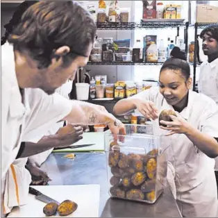  ?? TERRENCE ANTONIO JAMES/CHICAGO TRIBUNE PHOTOS ?? Sherita Cresswell, right, and other participan­ts at Inspiratio­n Kitchens food service job training program, select potatoes to use in a knife skills class on the West Side of Chicago on Monday.