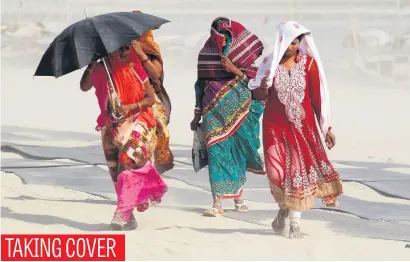  ?? Picture: Reuters ?? Women make their way along the banks of the river Ganges during a dust storm in Allahabad, India.