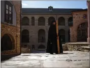  ?? THANASSIS STAVRAKIS — THE ASSOCIATED PRESS ?? A monk using a mallet and plank to summon monks and visitors to the afternoon prayers pauses at the Pantokrato­r Monastery in the Mount Athos, northern Greece, Oct. 13.