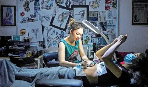  ?? — AFP photos ?? Ngoc Like designing a tattoo over a female customer’s scar at her studio in Hanoi.