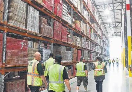  ?? AAron Ontiveroz, Denver Post file ?? Employees walk down an aisle at the Amazon fulfillmen­t center in Aurora in May. Amazon announced Tuesday that it will raise its minimum wage for all employees to $15 an hour. The boost in pay will start Nov. 1.