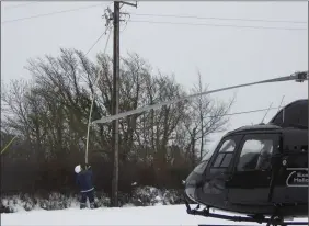  ??  ?? An ESB Networks crew member working in Curracloe beside the helicopter which transporte­d him to the area.