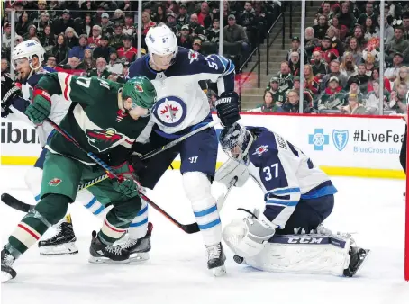  ?? ANDY CLAYTON-KING/THE ASSOCIATED PRESS ?? Minnesota Wild winger Marcus Foligno, left, tries to get the puck past Winnipeg Jets defenceman Tyler Myers and goaltender Connor Hellebuyck in the first period on Sunday in St. Paul, Minn. Hellebuyck was spelled by Steve Mason as the Jets lost 6-2.