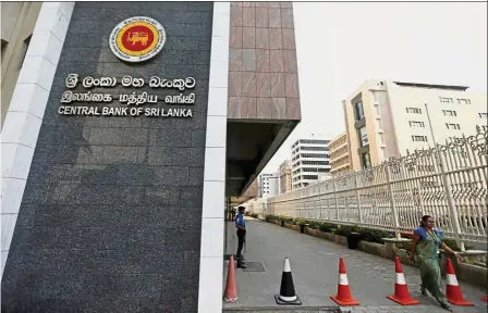  ??  ?? IMF proposals: A woman walks past the main entrance of Sri Lanka’s Central Bank in Colombo. The IMF has urged Sri Lanka to accelerate implementa­tion of structural reforms in public financial management and state-owned enterprise­s. — Reuters