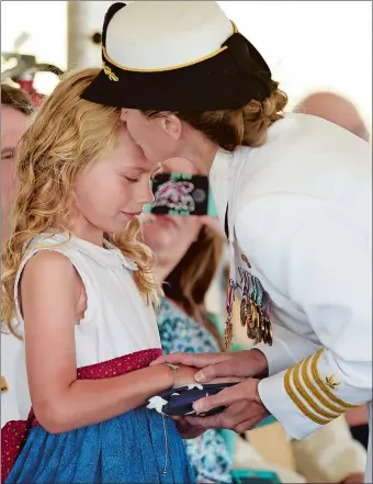  ?? SEAN D. ELLIOT/THE DAY ?? U.S. Navy Capt. Darlene Grasdock kisses her daughter Alexis, 9, after presenting her with the flag given to Grasdock as part of her retirement ceremony, concluding the change of command ceremony Friday on the grounds of Fort Trumbull State Park in New...