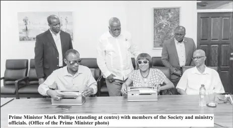  ?? ?? Prime Minister Mark Phillips (standing at centre) with members of the Society and ministry officials. (Office of the Prime Minister photo)