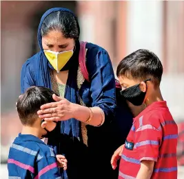  ??  ?? A mother, wearing a facemask amid concerns over the spread of the COVID-19 novel coronaviru­s, helps her son to wear a facemask as they visit the Jama Masjid mosque in the old quarters of New Delhi on March 13, 2020. (Photo by Jewel SAMAD / AFP)