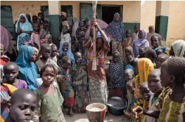  ?? — AFP ?? A woman (above) pounds food at a camp for internally displaced people in Dikwa, Nigeria. A man (right) sweeps the floor of a warehouse where relief materials are kept for displaced people following Boko Haram attacks in Borno State.