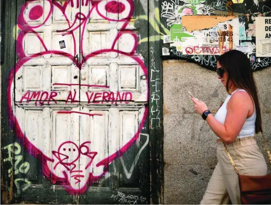 ?? EFE ?? Una joven pasea por delante de una puerta «grafiteada»