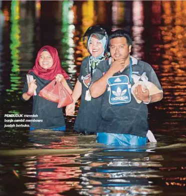  ??  ?? PENDUDUK meredah banjir sambil membawa juadah berbuka.