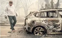  ?? NOAH BERGER THE ASSOCIATED PRESS ?? Eric England searches through a friend’s vehicle after the wildfire destroyed Paradise, a town of 26,000 people.