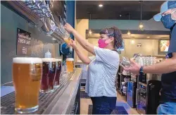  ?? EDDIE MOORE/JOURNAL ?? Eve Paz, a server, and Kris Lopez, the manager at Bosque Brewing’s Market Station Public House in the Santa Fe Rail Yard, pour beers for customers in September. The company was able to convert its $1.1 million loan through the Paycheck Protection Program into a grant earlier this year.