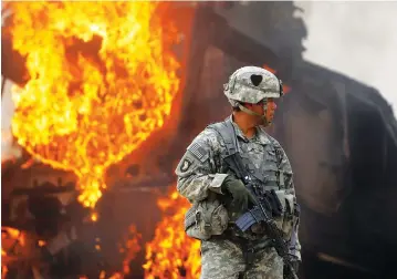  ?? (Bob Strong/File Photo/Reuters) ?? A US ARMY officer stands near a burning vehicle north of Kandahar, Afghanista­n.