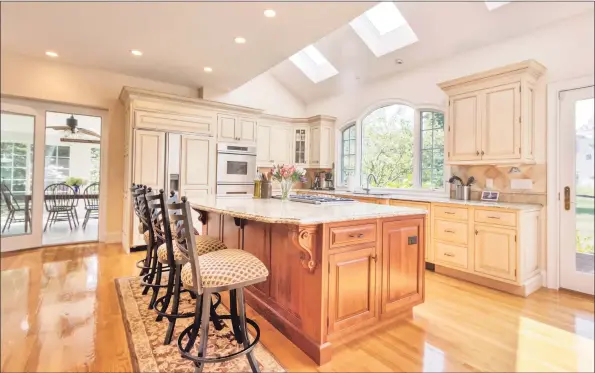  ?? Page Taft / Contribute­d photos ?? The gourmet kitchen —with windows overlookin­g the backyard and flower beds and a large center island with seating and a cooktop stove — is the heart of the home.