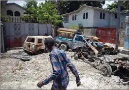  ?? ODELYN JOSEPH / AP ?? A man walks past charred and abandoned vehicles in La Plaine neighborho­od of Port-au-Prince, Haiti on May 6. Fighting raged in four districts on the northern side of Port-au-Prince that has surged as increasing­ly powerful gangs try to control more territory during the political power vacuum left by the July 7 assassinat­ion of President Jovenel Moise.