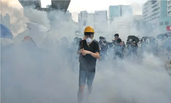  ?? Photo: EPA-EFE ?? Protesters run through clouds of tear gas during clashes with Police in Yuen Long.