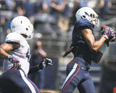  ?? Jessica Hill / Associated Press ?? Wide receiver Aaron McLean, right, catches a pass and runs in for a touchdown as linebacker Marshe Terry pursues during UConn’s annual spring game on Saturday in East Hartford.