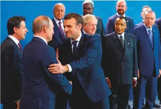  ?? AFP ?? ■ Emmanuel Macron shakes hands with Vladimir Putin before the Peace summit on Libya at the Chanceller­y in Berlin yesterday as other world leaders watch. The world leaders agreed to respect an arms embargo on Libya.