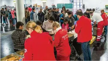  ??  ?? In der Messehalle A wurde Essen ausgegeben. Feldbetten waren für die erschöpfte­n Flüchtling­e vorbereite­t