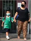  ??  ?? „ A mother and child wear face masks on the school run.