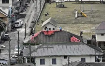  ?? Orvil Samuel/Associated Press ?? People clean volcanic ash from the red roof of a home after La Soufriere volcano erupted Monday in Wallilabou, on the western side of the Caribbean island of St. Vincent.