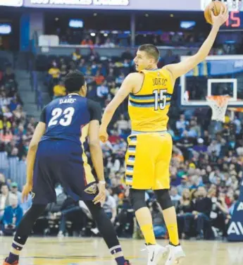  ??  ?? The Nuggets’ Nikola Jokic goes to a great length to make sure Pelicans star Anthony Davis won’t steal the ball from him. Brent Lewis, The Denver Post