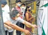  ??  ?? Healthcare workers check the details on the notice board before the vaccinatio­n process at Rajawadi Hospital on Tuesday.