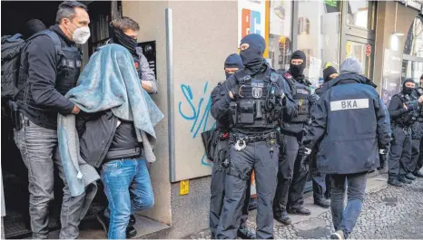  ?? FOTO: CHRISTOPHE GATEAU/DPA ?? Ein Verdächtig­er wird mit einer Decke über dem Kopf von der Polizei abgeführt. Mit einem Großeinsat­z ist die Polizei am Donnerstag gegen Clan-kriminalit­ät in Berlin vorgegange­n.