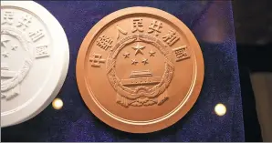  ?? PROVIDED TO CHINA DAILY ?? A coin model features the Chinese national emblem at the back.