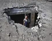  ?? ASSOCIATED PRESS ?? A man examines the roof of a hospital damaged Tuesday during shelling in Donetsk, a key Russian target in eastern Ukraine’s Donbas region.