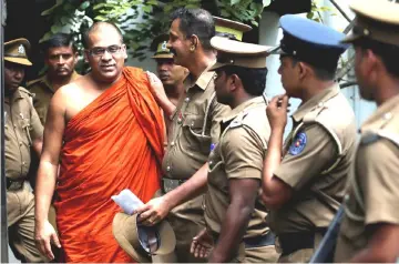  ??  ?? Gnanasara walks towards a prison bus while accompanie­d by prison officers after he was sentenced by the court in Homagama, Sri Lanka. — Reuters photo