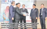  ??  ?? Dato’ Sri Ismail Sabri Yaakob menyampaik­an hadiah tempat pertama Anugerah Inovasi Perkhidmat­an Awam (Teknikal) kepada Ketua Pengarah RISDA.