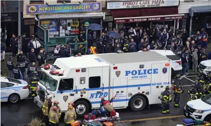  ?? Photograph: John Minchillo/AP ?? Emergency personnel gather at the entrance to a subway station in Brooklyn after the rush-hour shooting on 12 April.