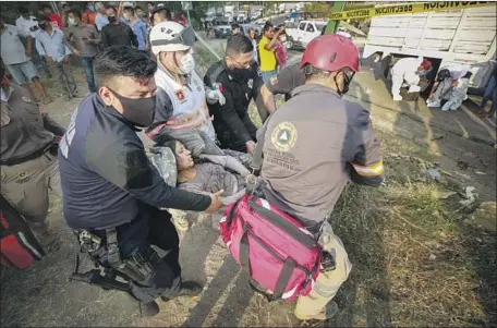 ?? Associated Press ?? RESCUE WORKERS move an injured woman from the site of a tractor-trailer crash in the Mexican state of Chiapas on Thursday. At least 55 people were killed and dozens injured when a truck smuggling migrants careened into a bridge near the city of Tuxtla Gutiérrez.