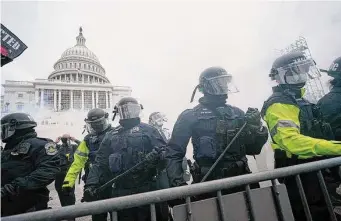  ?? Julio Cortez/Associated Press ?? Police stand guard after holding off rioters who tried to break through a police barrier at the Capitol in Washington on Jan. 6, 2021. New London submarine engineer Jeremy Baouche was sentenced for his role in the Jan. 6 riot Wednesday, according to federal officials.