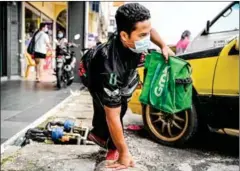  ?? AFP ?? Muhammad Sidek Osman, a Grab food delivery man born disabled due to birth complicati­ons, carries orders towards his modified motorbike outside a restaurant in Gombak.