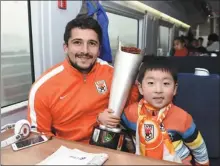  ?? XINHUA ?? Aloisio poses with a young fan on board a high-speed train after Shandong Luneng’s victory over Guangzhou Evergrande in the 2015 CFA Super Cup final in Hangzhou.