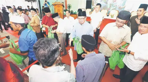  ??  ?? Abang Johari (front facing camera, third right) distribute­s the ‘Bubur Masja-Sa’ to the visitors after the ceremony at Masjid Jamek in Kuching. — Photos by Chimon Upon