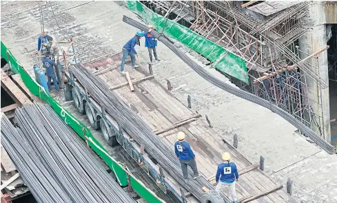  ?? THANARAK KHUNTON ?? Workers unload steel rods at a constructi­on site on Sukhumvit Road. G Steel expects a healthy outlook for the steel industry next year.