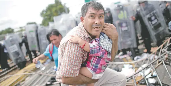  ??  ?? Un migrante hondureño protege a su hijo después de que sus compañeros de la caravana irrumpiero­n en un puesto fronterizo en Guatemala, en Ciudad Hidalgo, México.